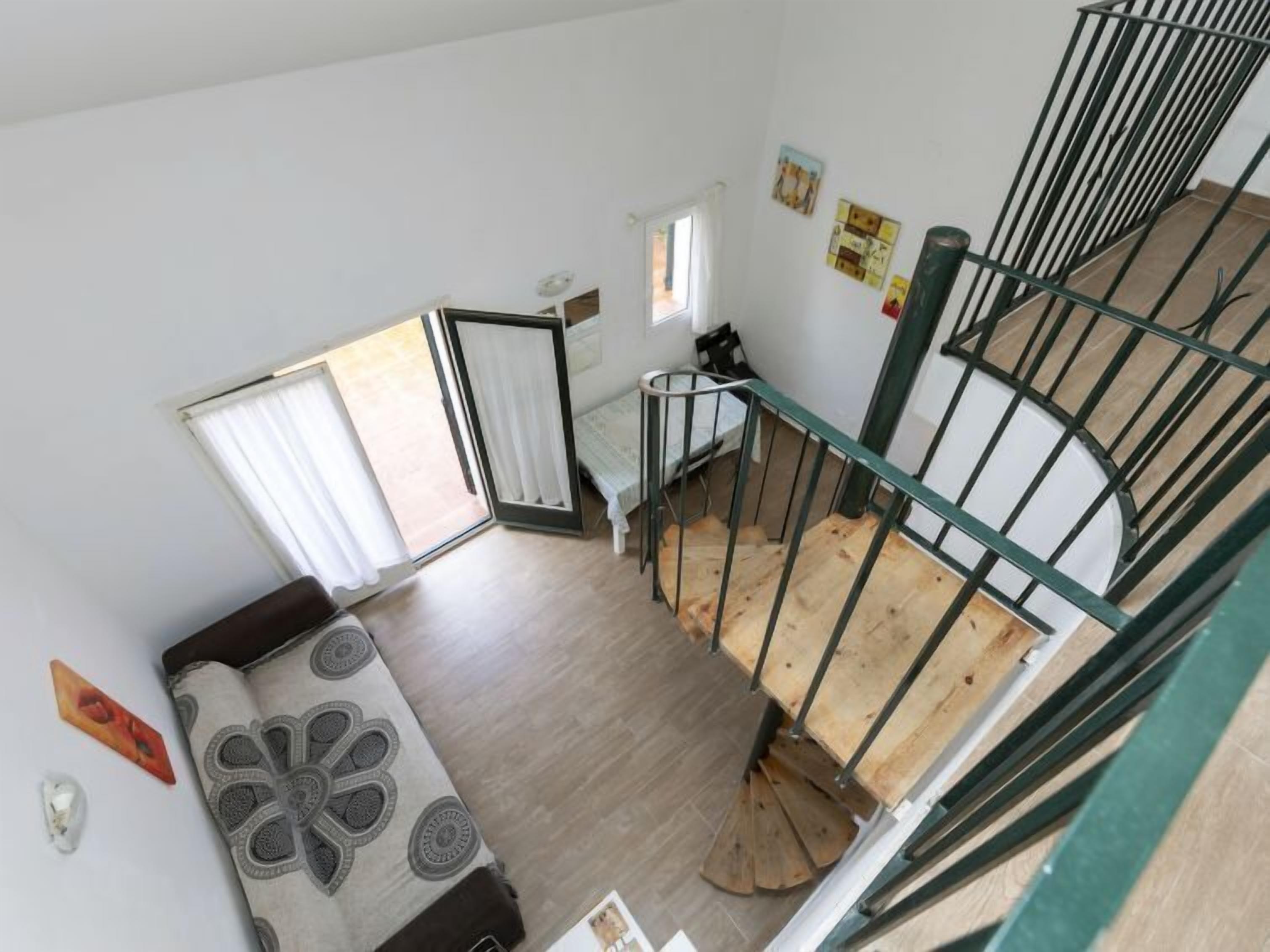 A room with a bed, a window, a staircase, and a door.