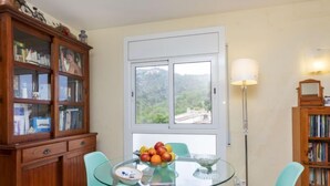 Un comedor con una mesa de vidrio, dos sillas, un frutero y un mueble de madera con puertas de cristal.