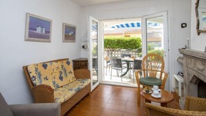 A cozy living room with a sofa, a dining table with chairs, a fireplace, and a balcony with outdoor seating. - Vacation home Marie by Interhome (L'Escala)