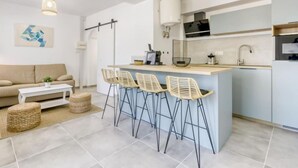 Een moderne keuken met een centraal eiland, barkrukken, een bank en een salontafel.