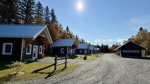 A row of cabins with metal roofs, surrounded by trees and a gravel path. - Dôme #2 Situé en pleine nature (Saint-Gabriel-de-Valcartier)