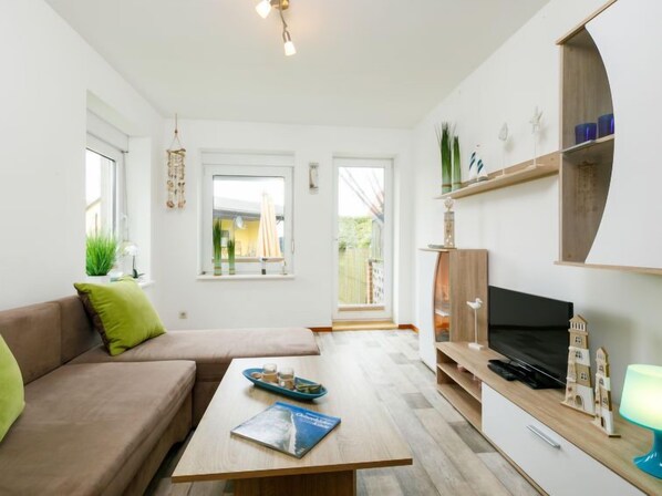 A modern living room with a sofa, coffee table, TV, and shelves.
