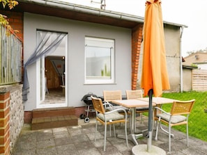 A patio with a table and chairs, a grill, and a covered area with an umbrella.