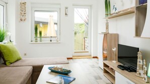 A modern living room with a sofa, coffee table, TV, and a view of the outside. - Ruprecht by Interhome (Zinnowitz)
