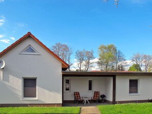 Ein zweistöckiges Haus mit überdachter Terrasse, einer Satellitenschüssel und einem kleinen Fenster.