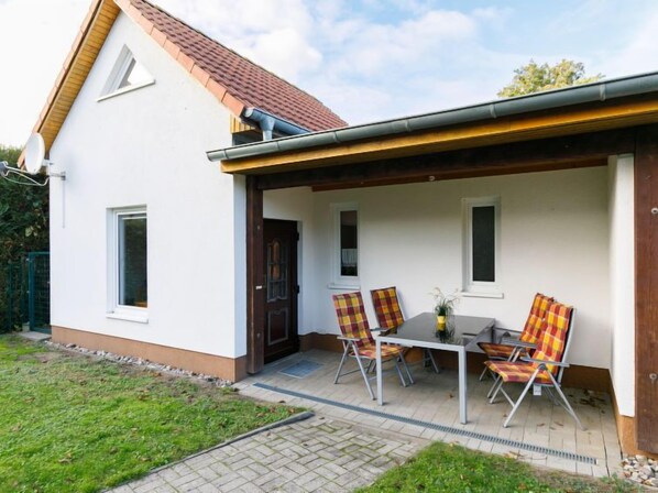 Ein Haus mit überdachter Terrasse, einem Esstisch und Stühlen.