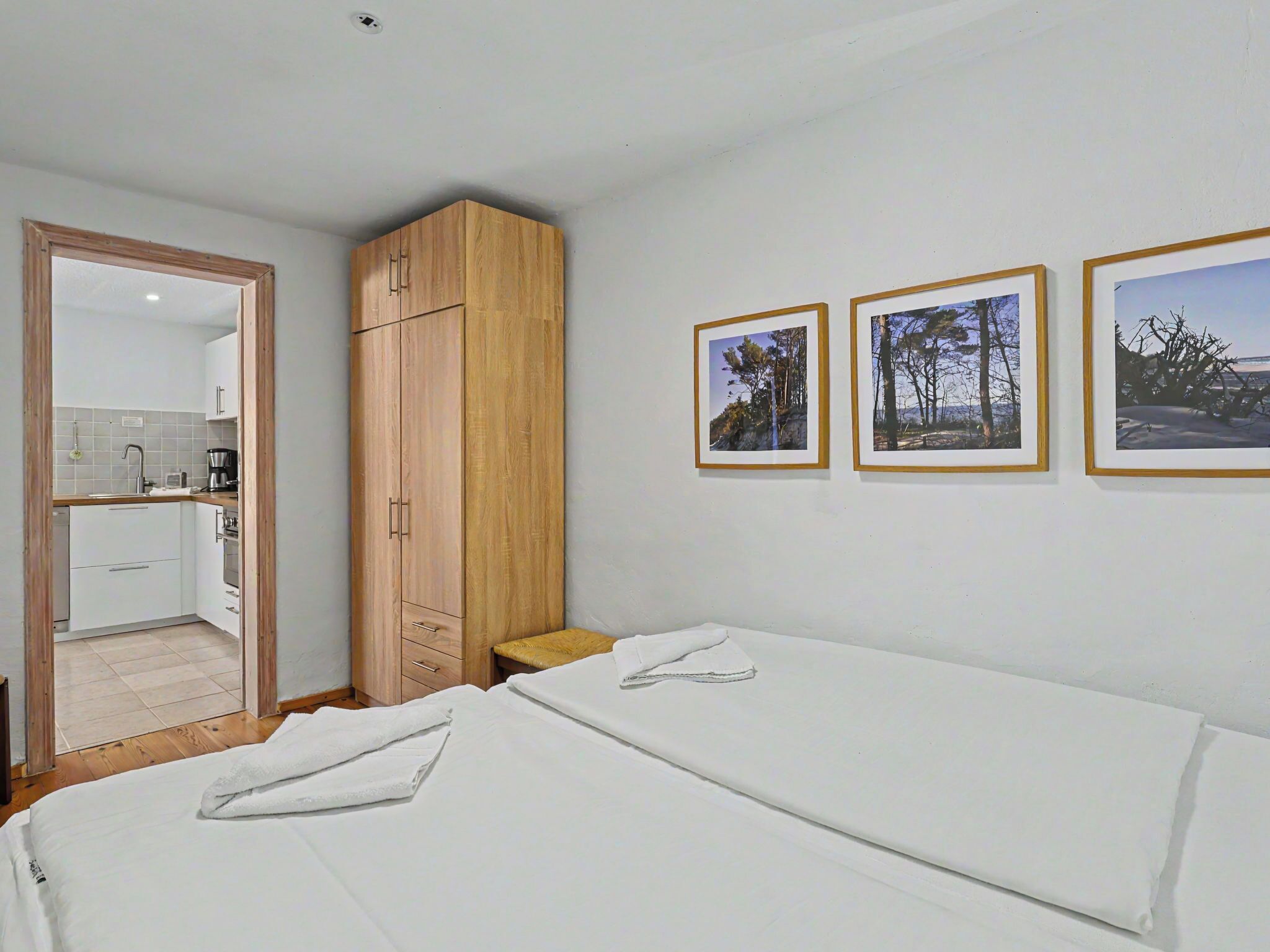 Una camera da letto con un letto, un armadio in legno, un tavolino e tre quadri appesi al muro.
