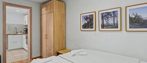 Una camera da letto con un letto, un armadio in legno, un tavolino e tre quadri appesi al muro.