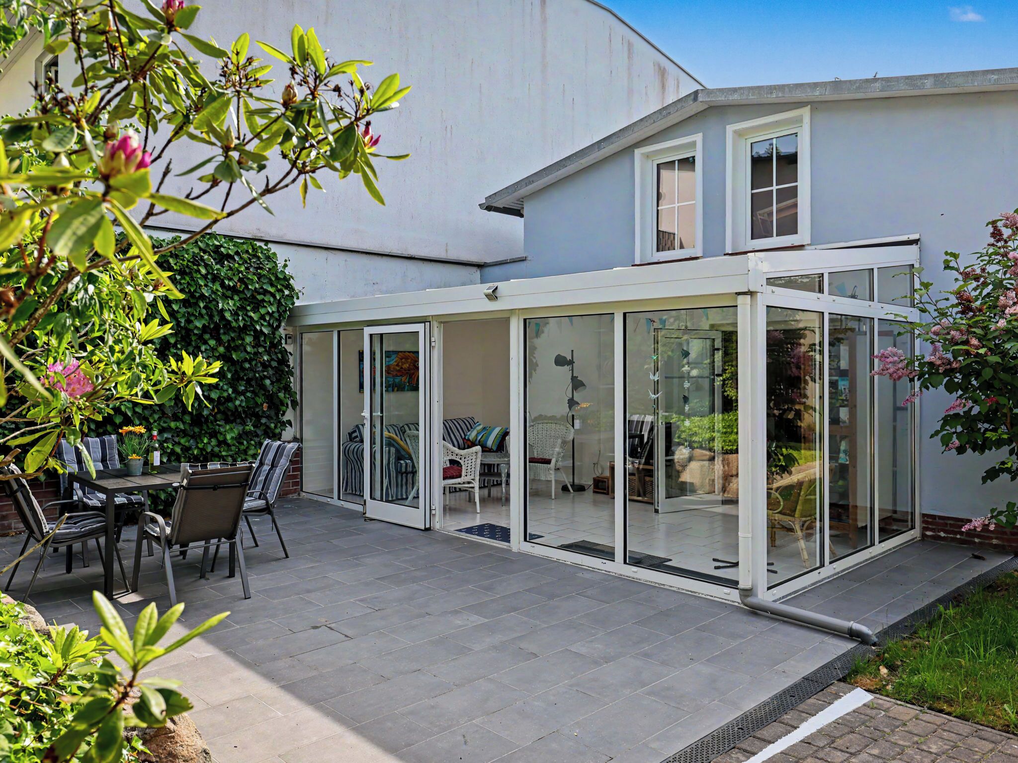 Et moderne hus med en veranda med glas, udendørs møbler og udsigt til indretningen.