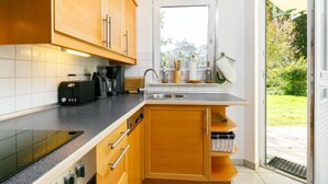 Eine kleine Küche mit Holdekor, Backofen, einer Kaffeemaschine und einem Fenster mit Blick auf einen Garten.