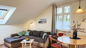 A cozy living room with a sectional sofa, a small wooden table, and a dining table with chairs. - Zaunkönig by Interhome (Zinnowitz)