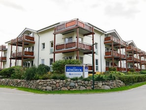 Ein mehrstöckiges Wohnhaus mit Balkonen, einer Steinmauer und einem Schild, das es als Wohnkomplex kennzeichnet.