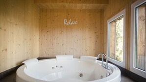Een moderne badkamer met een vrijstaand bad, houten wanden en een raam met uitzicht op de natuur.