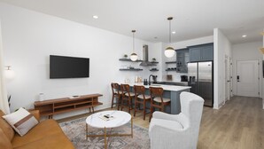A modern living room with a sofa, coffee table, and a TV mounted on the wall. - Chic East Nashville Condo -Free Parking 3 miles to Broadway (Nashville)