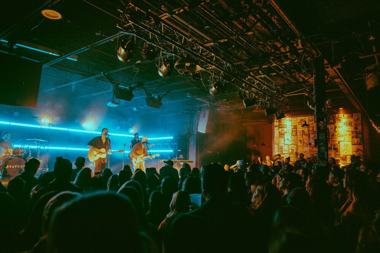 Un concert où un groupe joue sur scène, entouré de spectateurs.