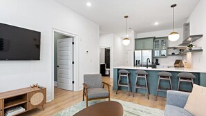 Un salon moderne avec un téléviseur à écran plat, un meuble de rangement en bois et un canapé.