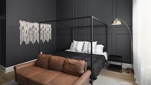 A modern bedroom with a four-poster bed, a leather sofa, and a decorative wall hanging. - Luxury 6 Bed 3 Bedroom Walk to Restaurants +Coffee (Nashville)