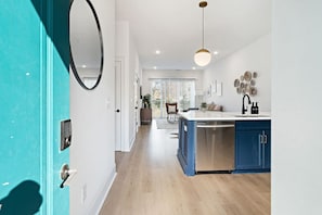 A modern kitchen with a central island, blue cabinets, and a stainless steel dishwasher.