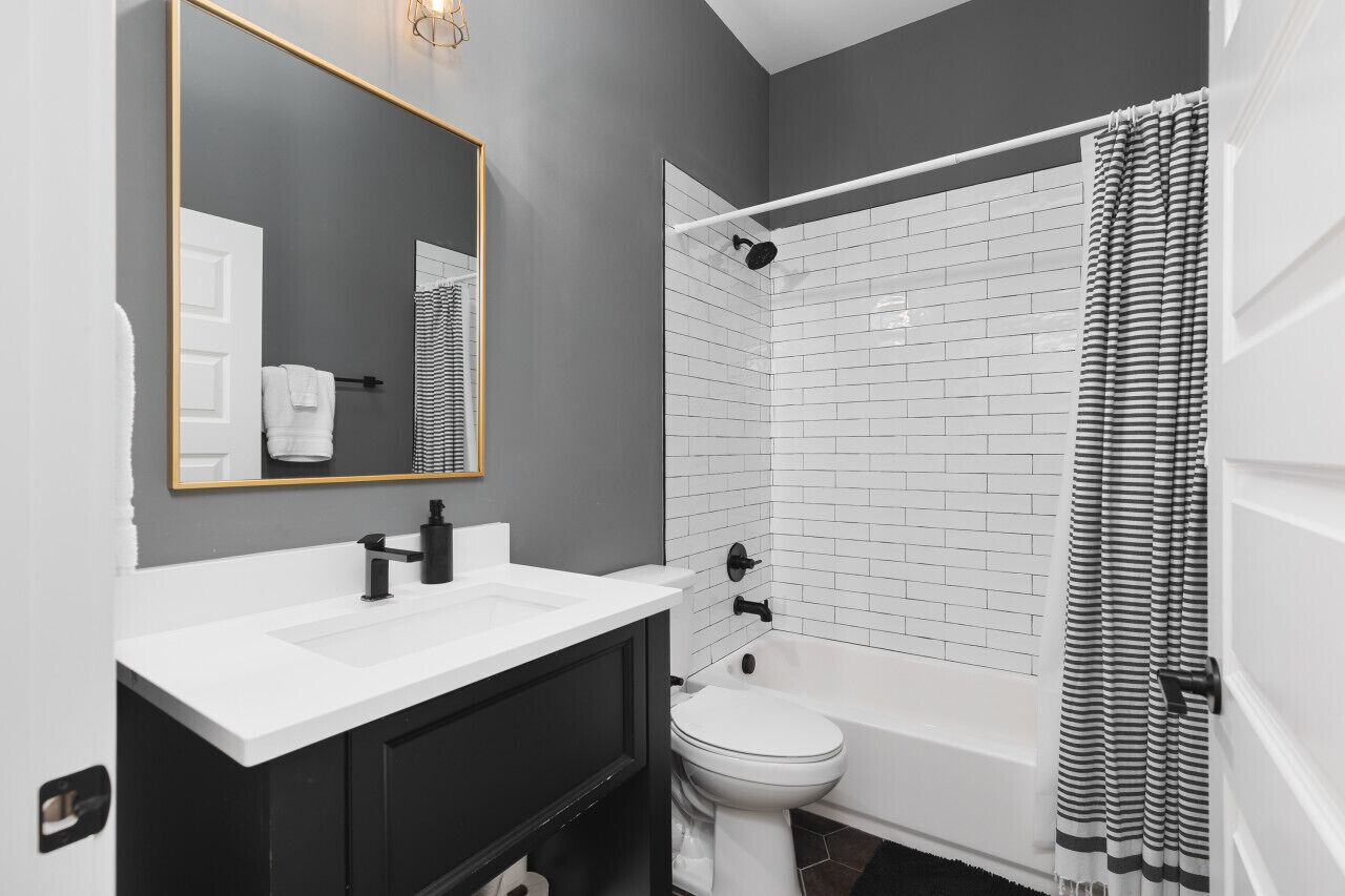 Un baño moderno con lavamanos blanco, grifo negro y retrete blanco.