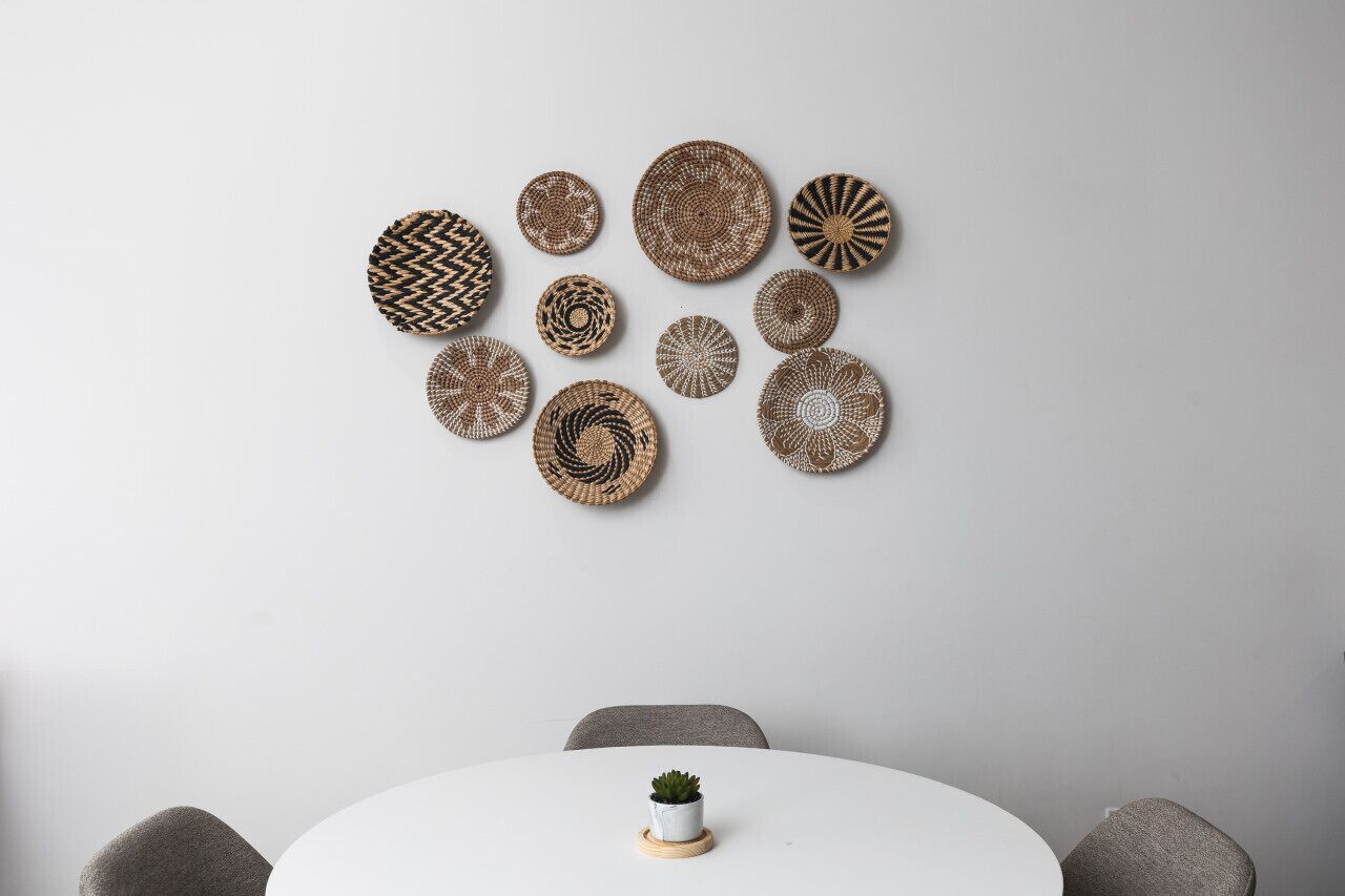 Een eethoek met een ronde tafel, grijze stoelen en een kleine potplant op tafel.