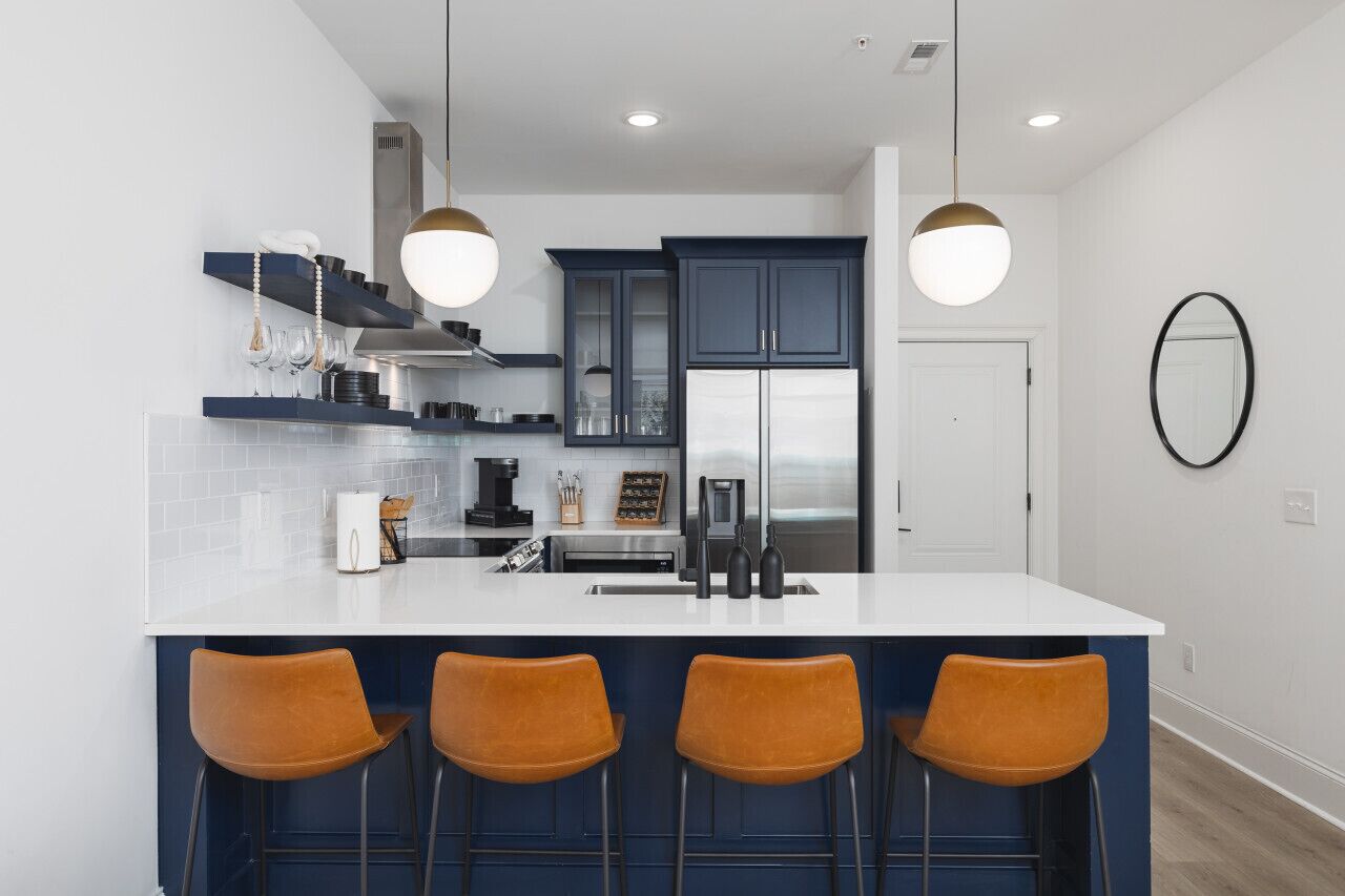 A modern kitchen with a central island, bar stools, and pendant lighting.