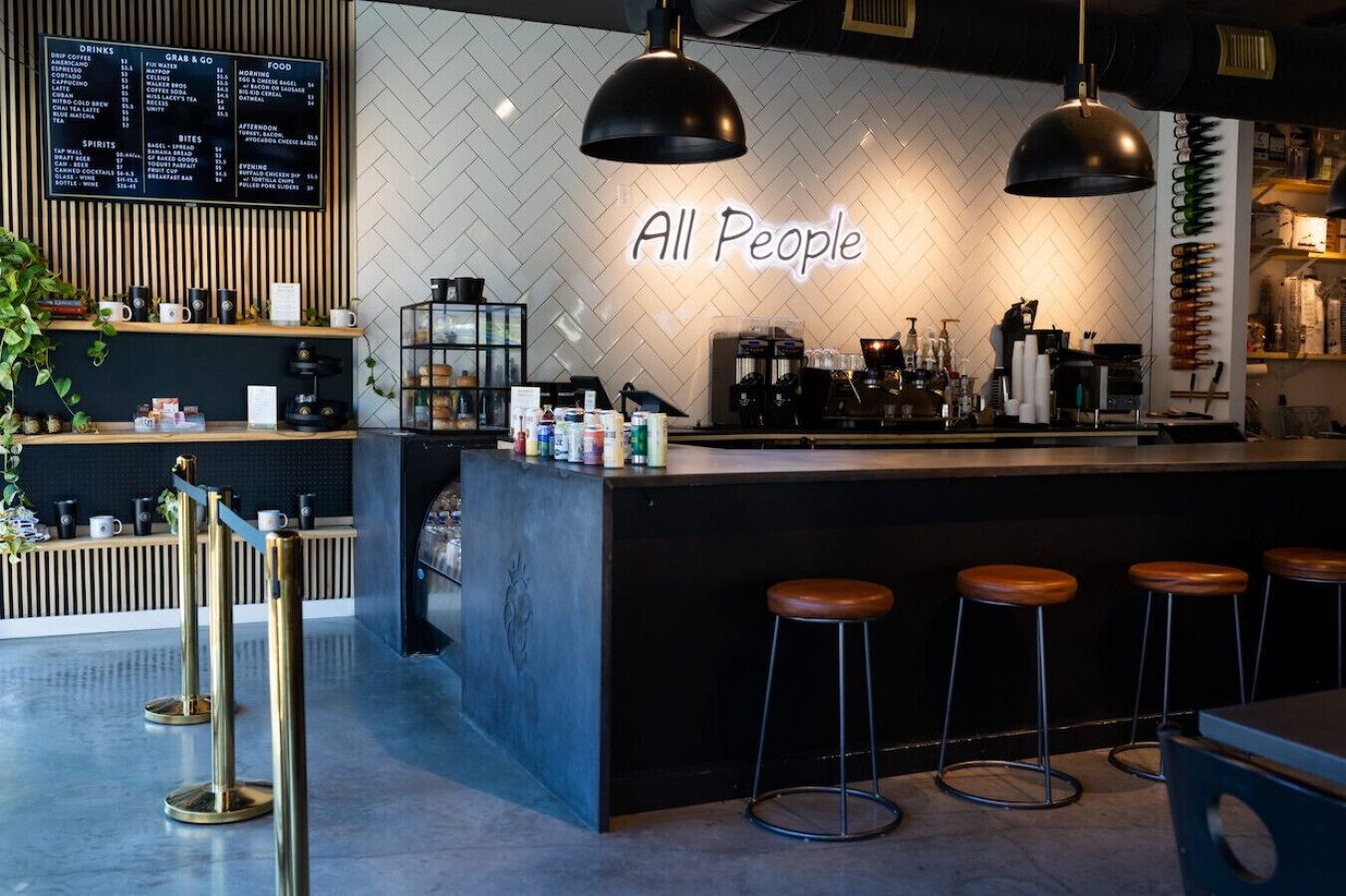 A modern bar area with a menu board, bar stools, and a neon sign that reads "All People".