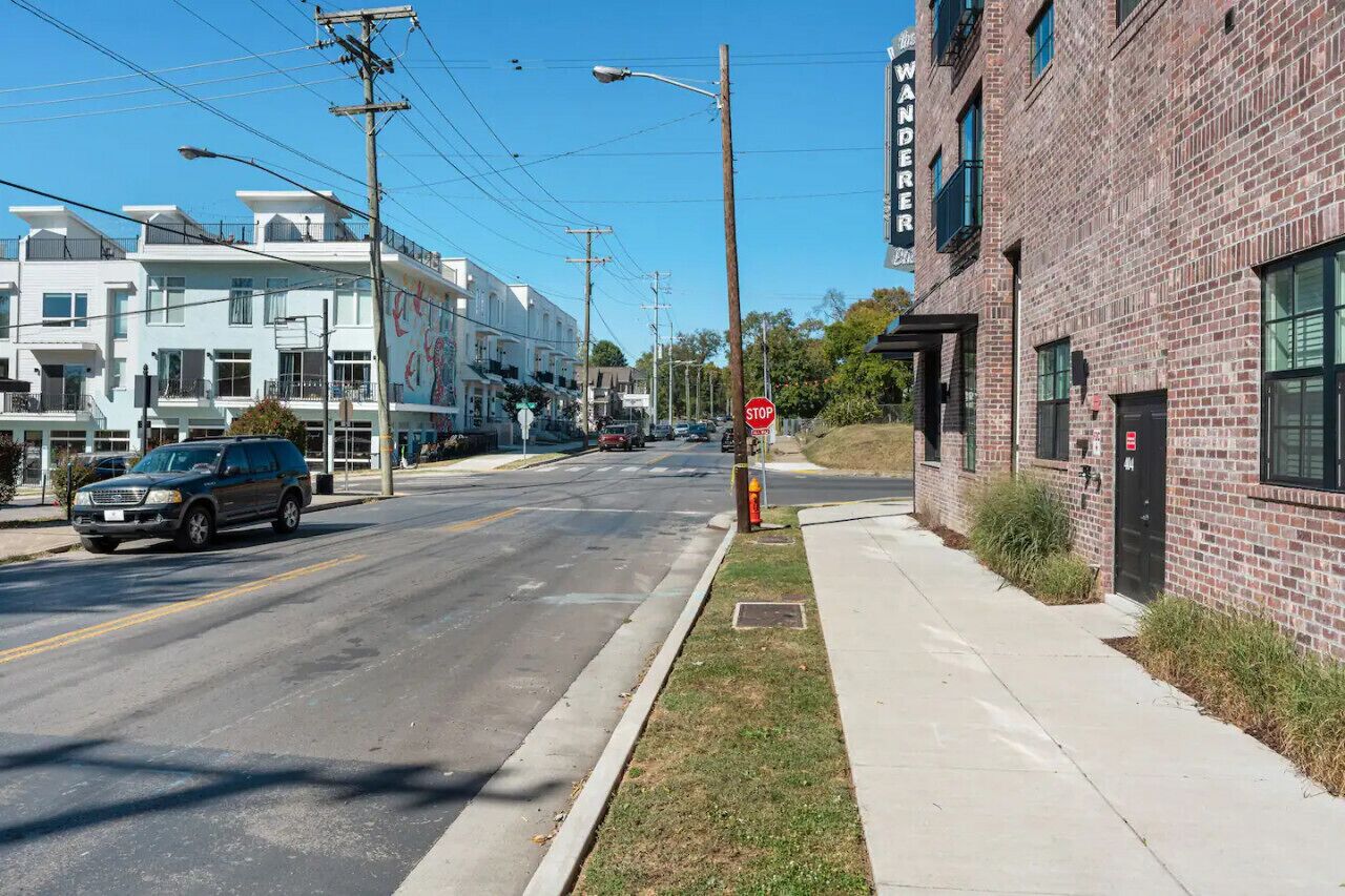 A street view with a stop sign, a brick building, and a multi-story white building with balconies.