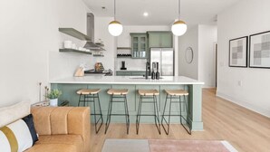 Una cocina moderna con una isla central, taburetes de bar e iluminación colgante.