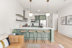 A modern kitchen with a central island, bar stools, and pendant lighting.