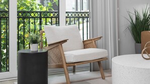 Un salón moderno con una silla de madera, una mesita auxiliar negra y una mesa redonda blanca.