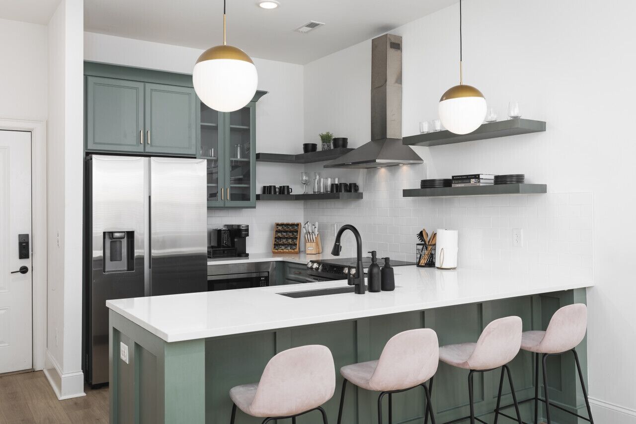 A modern kitchen with a central island, bar stools, and pendant lighting.