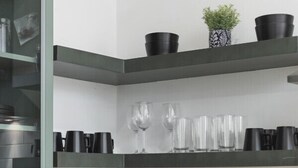 A kitchen with white tiled backsplash, black appliances, and a coffee machine. There are black mugs on the shelf and a plant in a black pot. - Condo with Free Parking, 3 miles Downtown, near Restaurants (Nashville)
