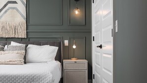 A bedroom with a bed, nightstands, and a door. - Chic and Cozy Designer Condo 3 Miles to Downtown (Nashville)