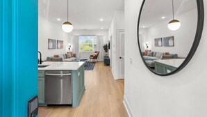 A modern kitchen with a central island, a dining area with a sofa and chairs, and a large mirror on the wall. - Chic and Cozy Designer Condo 3 Miles to Downtown (Nashville)