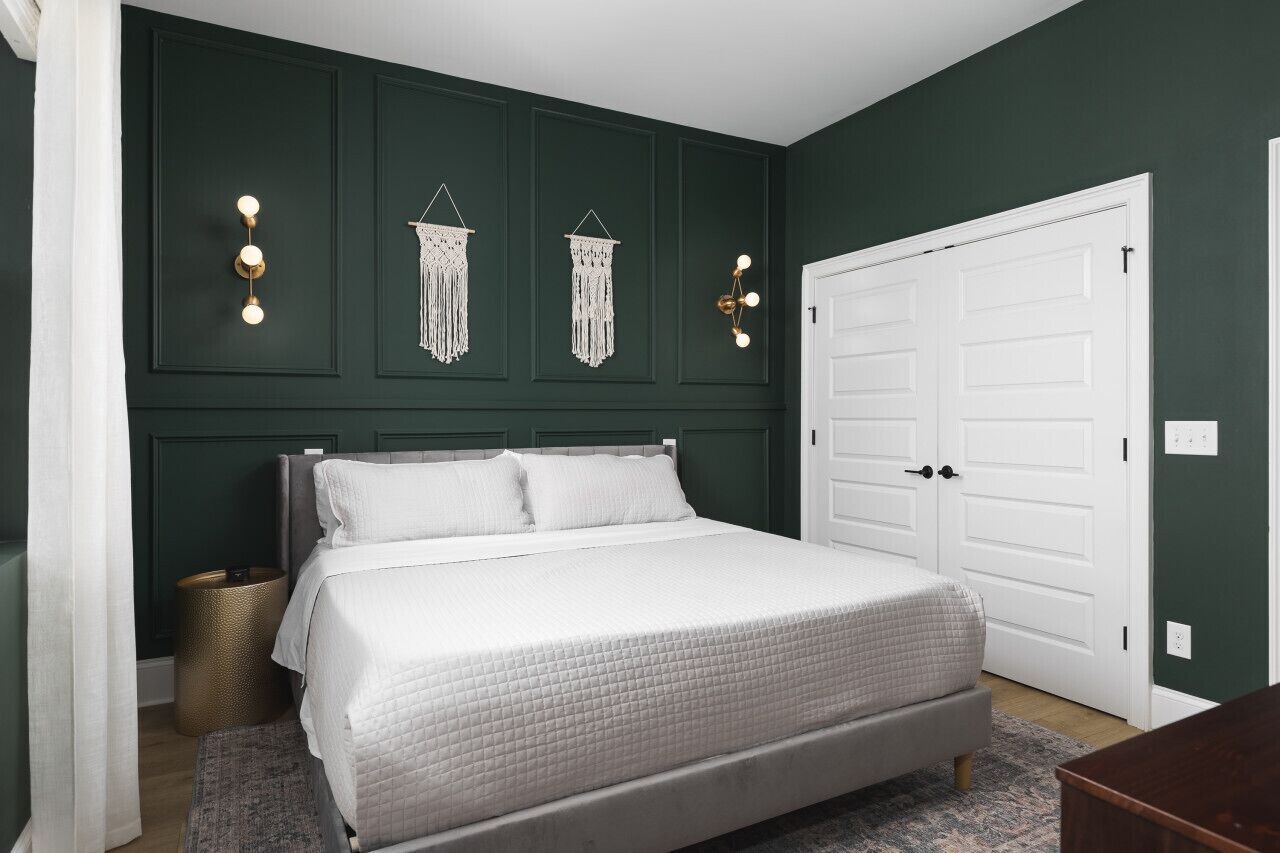 Quarto com cama, porta branca e luminárias fixadas na parede.
