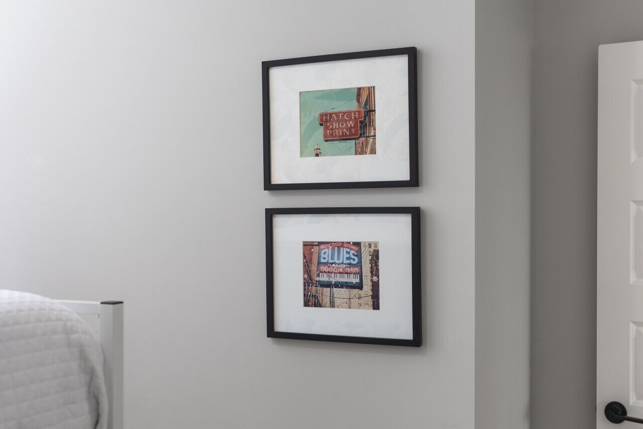 Two framed pictures on a wall, one with a sign reading "HATCH SHOW PRINT" and another with "BLUES".