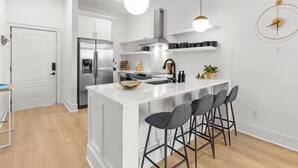Een moderne keuken met een centraal eiland, roestvrijstalen apparatuur en barstoelen.
