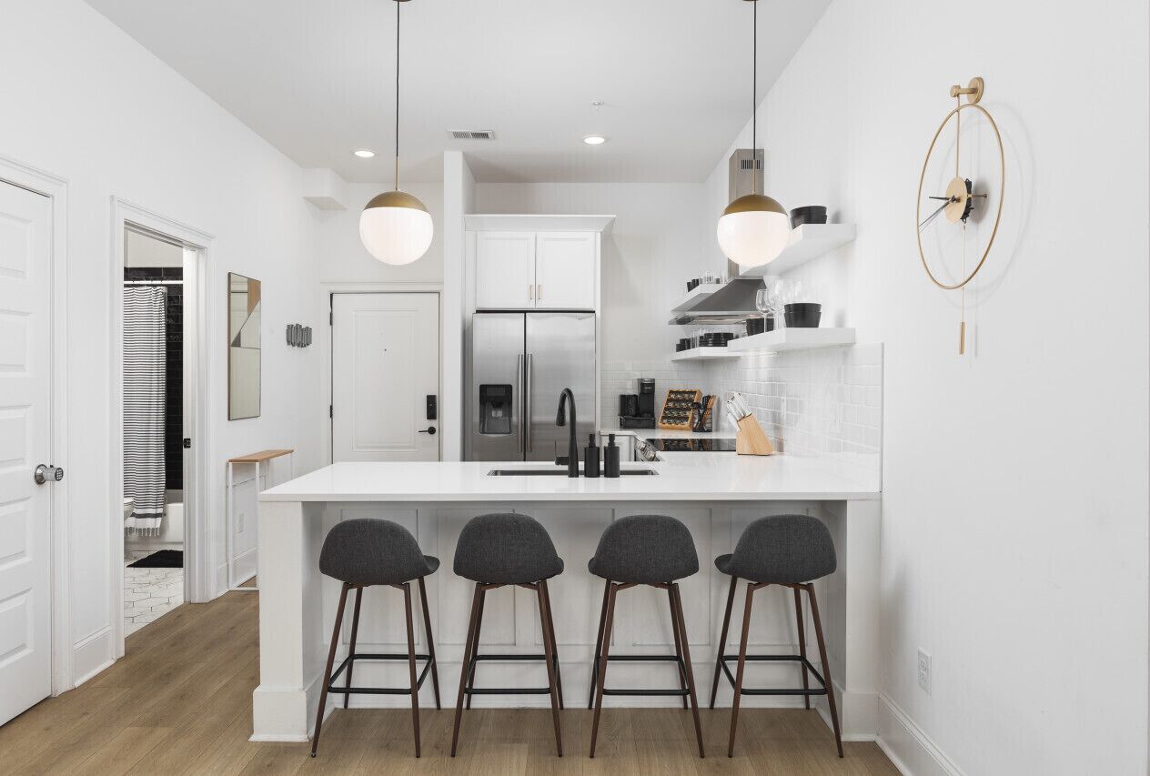 Una cocina moderna con una isla central, taburetes de bar e iluminación colgante.