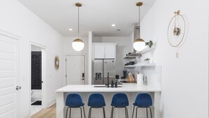 Uma cozinha moderna com ilha branca, banquetas e iluminação pendente.