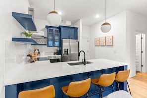 Une cuisine moderne dotée d’un grand îlot central, de meubles bleus et d’un plan de travail blanc.
