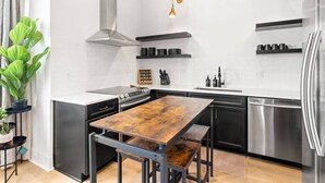 Una cocina moderna con una isla central, electrodomésticos de acero inoxidable e iluminación colgante.