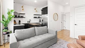 Una sala moderna con un sofá gris, una mesa de centro y una planta en maceta.