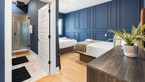 Ein modernes Schlafzimmer mit einem großen Bett, einem Nachttisch, einer Topfpflanze und einem begehbaren Kleiderschrank mit Spiegel.