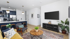 Ein modernes Wohnzimmer mit einer Couch, einem Couchtisch und einem an der Wand befestigten Fernseher.
