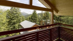 Un balcón de madera con vistas a un bosque y montañas.