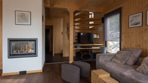 Una sala de estar acogedora con chimenea, un sofá, otomanas y un televisor.