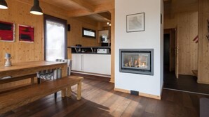 Un interior de madera con comedor, cocina y chimenea.