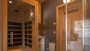 A sauna room with a wooden bench, a glass door, and a towel hanging on the wall.