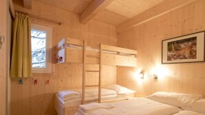 A cozy wooden cabin room with bunk beds, a window with curtains, a framed picture on the wall, and a small shelf with items. - #23 mir IR-Sauna und Sprudelbad Innen by Interhome (Turracher Höhe)