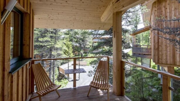 A wooden deck with two wooden chairs and a table, overlooking a forested area. - #23 mir IR-Sauna und Sprudelbad Innen by Interhome (Turracher Höhe)